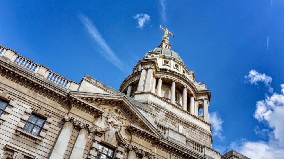 A white stone court building in England, with blue skies and clouds behind it
