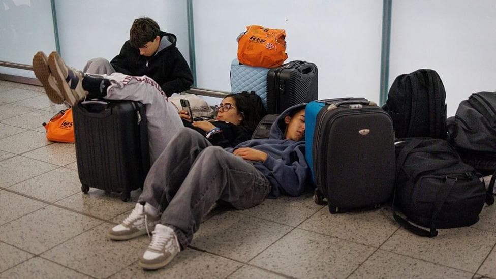 Young people lying on the floor of Gatwick Airport with their suitcases