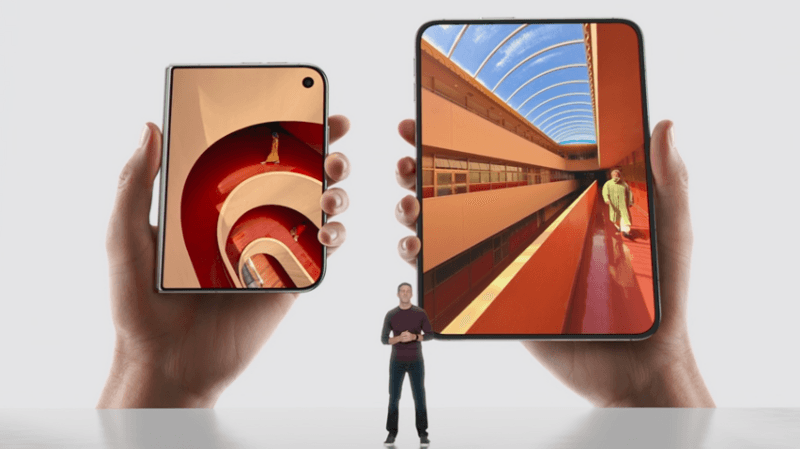 New Apple CEO John Ternus standing on a stage before two large images of the new foldable iPhone Duo.