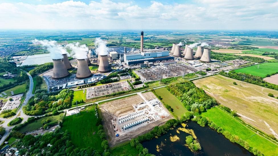 An aerial image of Drax power station showing several cooling towers set among a large site with buildings. The power station is surrounded by green land.
