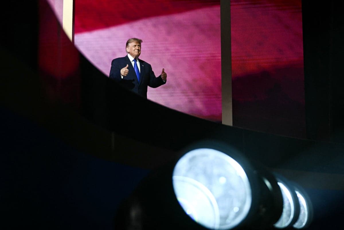 a man gives two thumbs up while on stage
