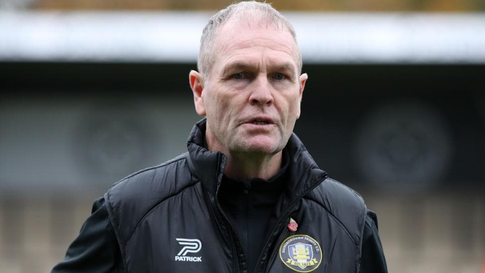 Russ Wilcox wearing a black jacket with a Gainsborough Trinity badge on the chest