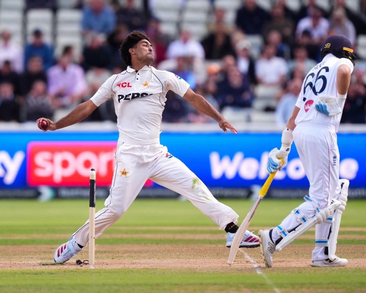 Pakistan's Razaullah bowls, leaning back with arm outstretched, as a batsman looks down nearby