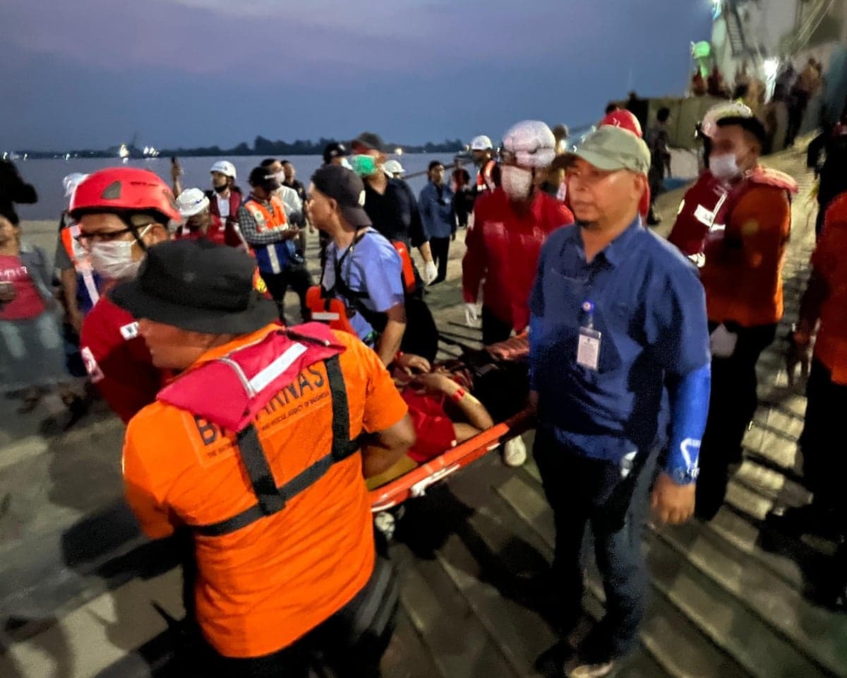 Rescue workers carry a survivor on a stretcher in a dock area