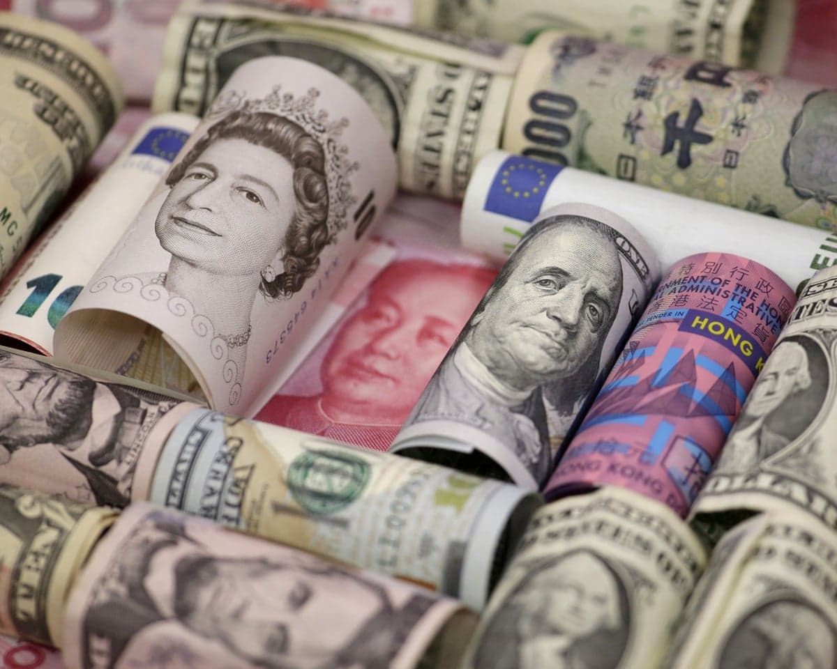 Rolled banknotes from various world currencies bundled together, showing portraits and colors