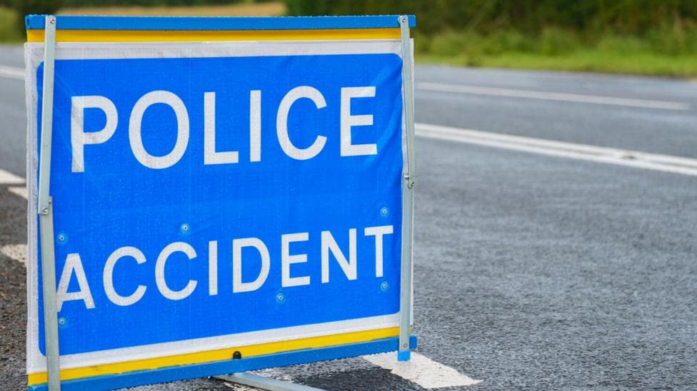 Blue police sign on a road with white writing that says Police Accident.