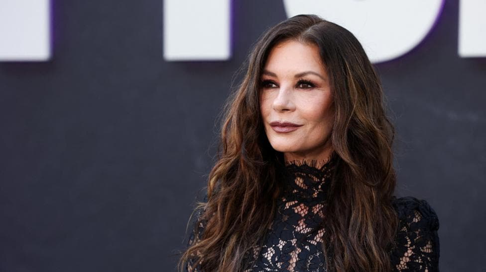 Catherine Zeta-Jones attends a For Your Consideration event for the television series "Wednesday" in Los Angeles, November 2025. She wears a black dress with lace detailing and wears her long brown hair down.