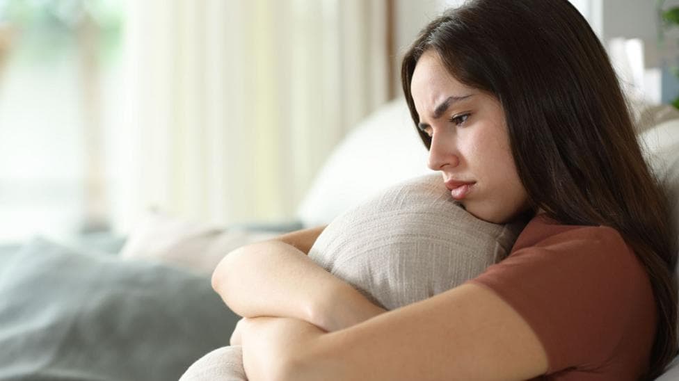 Disappointed looking young woman hugs a cushion.