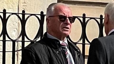 Alexander Hutcheon, a man with grey hair and glasses, wearing a shirt and tie and dark jacket, outside court.