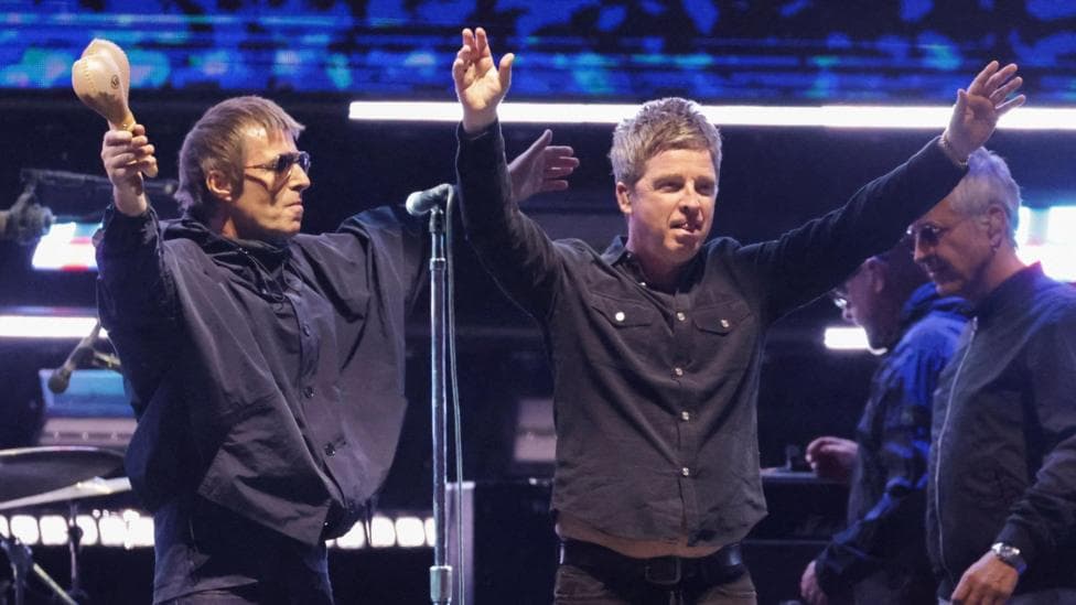 Liam and Noel Gallagher of Oasis with their arms outstretched accepting applause from the audience at the Rose Bowl Stadium in Pasadena, California in September 2025