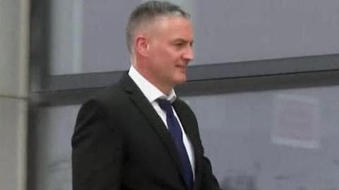PC Richard Williams seen walking outside in black suit and navy tie and white shirt. He has short grey hair.