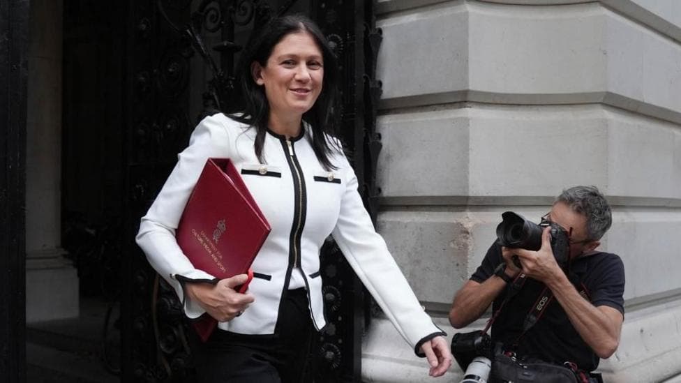 Lisa Nandy, wearing a white jacket, walks in Whitehall with a red brief case under her arm.