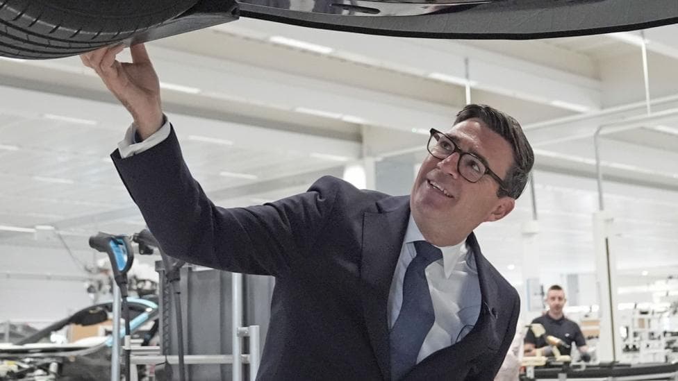Prime Minister Andy Burnham looks at a car on the production line during a visit