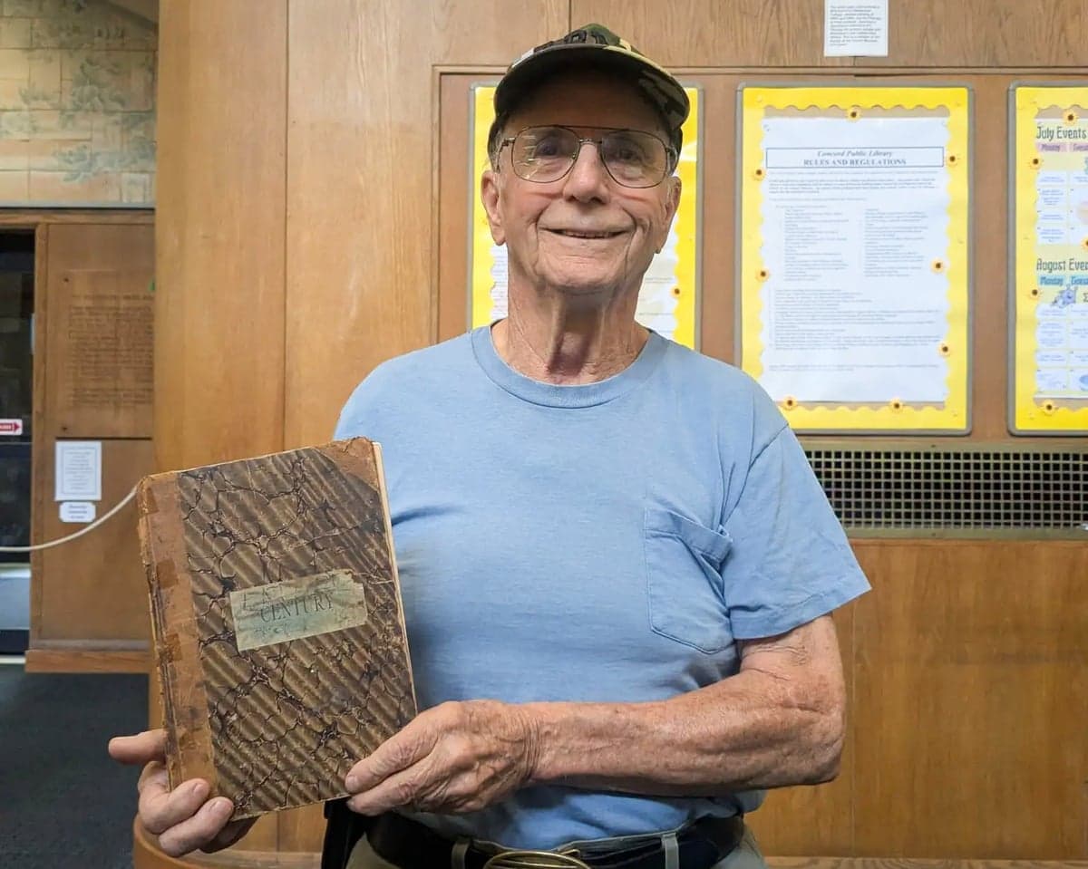 a man smiles while holding a magazine from 1894