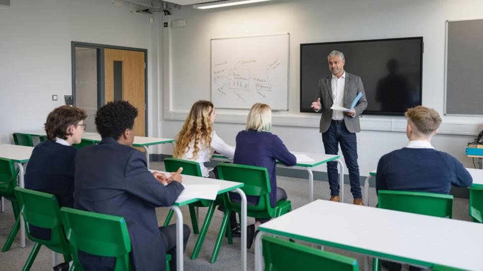 A teacher addressing pupils in a school classroom