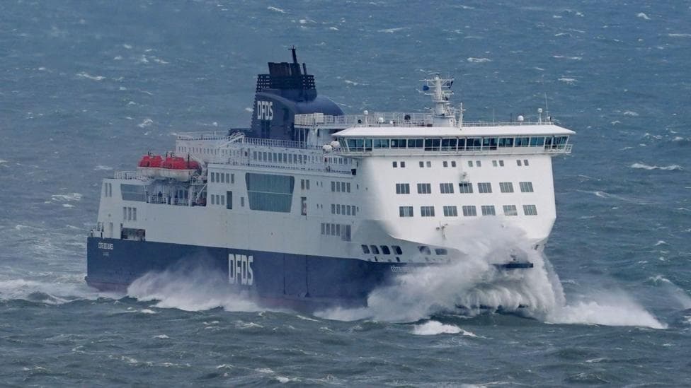A ferry arriving in UK waters. The ship is mainly white with a blue hull and the letters DFDS on it.