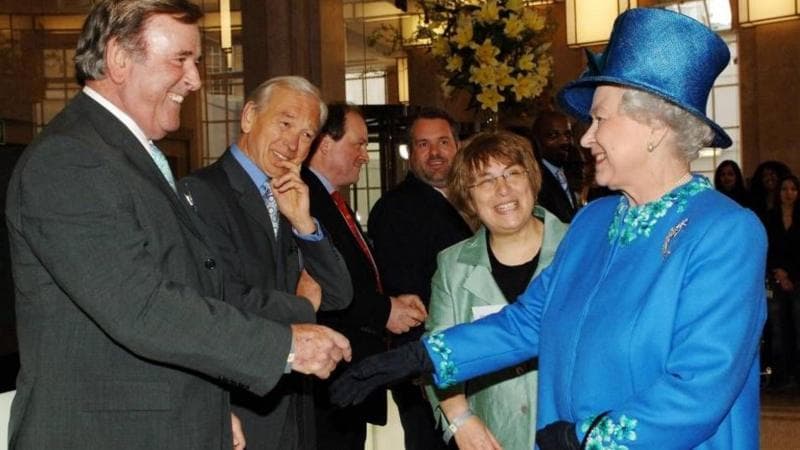 Queen Elizabeth II in blue meeting people in dark suits