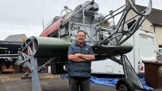 Julian Mitchell is standing in front of the frame of a 1941 Hawker Hurricane.