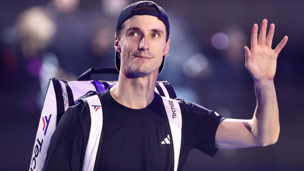 British tennis player Joe Salisbury waving with a tennis bag on his shoulder