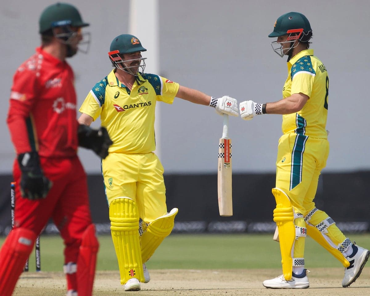 Travis Head celebrates with Mitchell Marsh on his way to a century against Zimbabwe