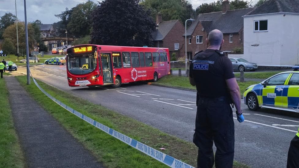 A bus reversed on to a kerb on a residential street with a police cordon in place