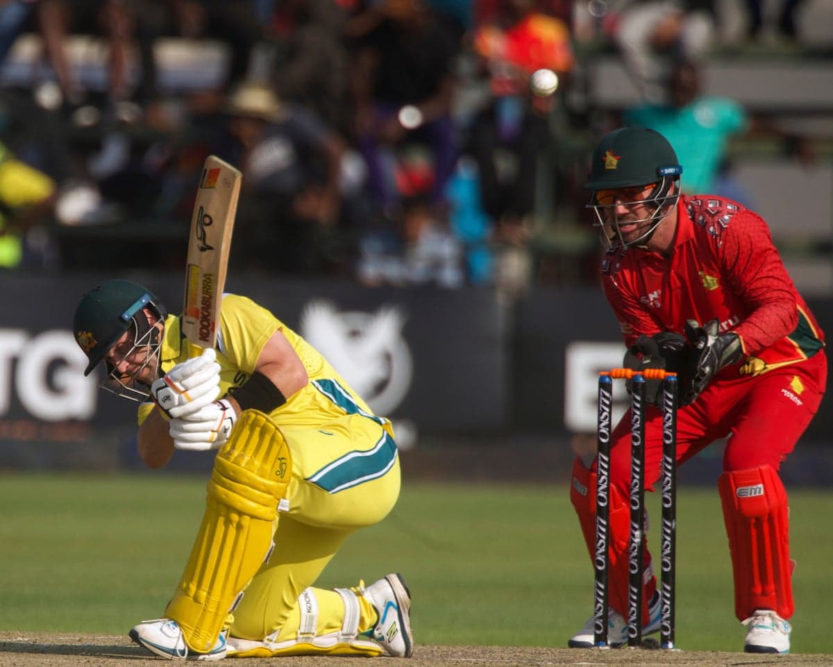 Australia's Josh Inglis plays a slog-sweep as Zimbabwe wicketkeeper Brendan Taylor looks on