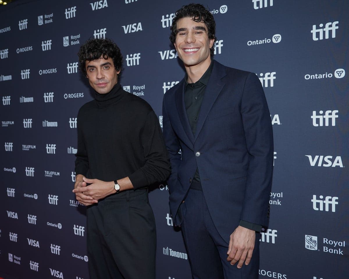two men standing on a red carpet