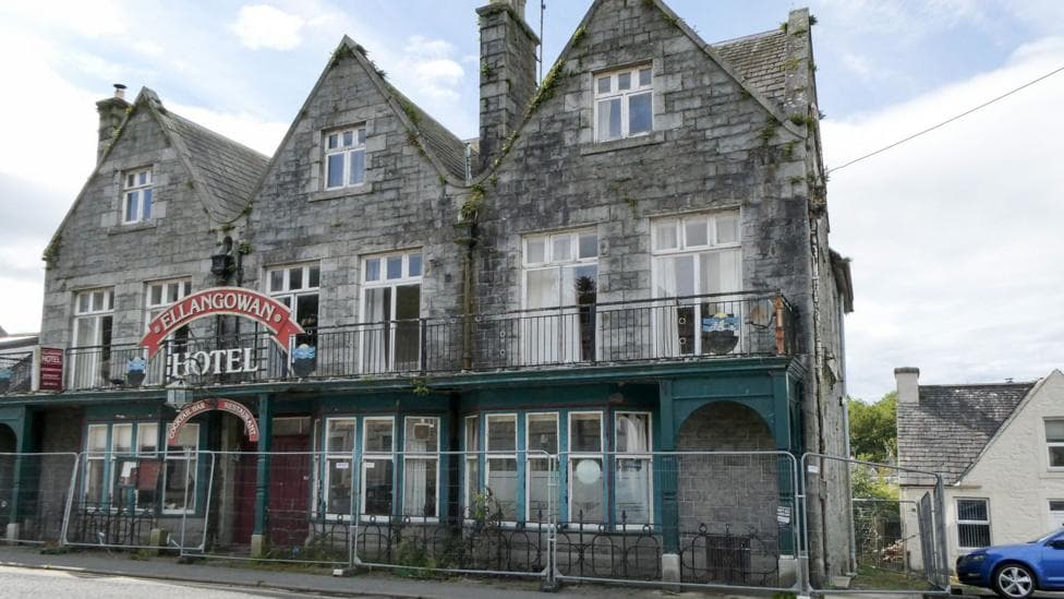 A run down hotel with barriers outside it with the Ellangowan Hotel sign above the door.