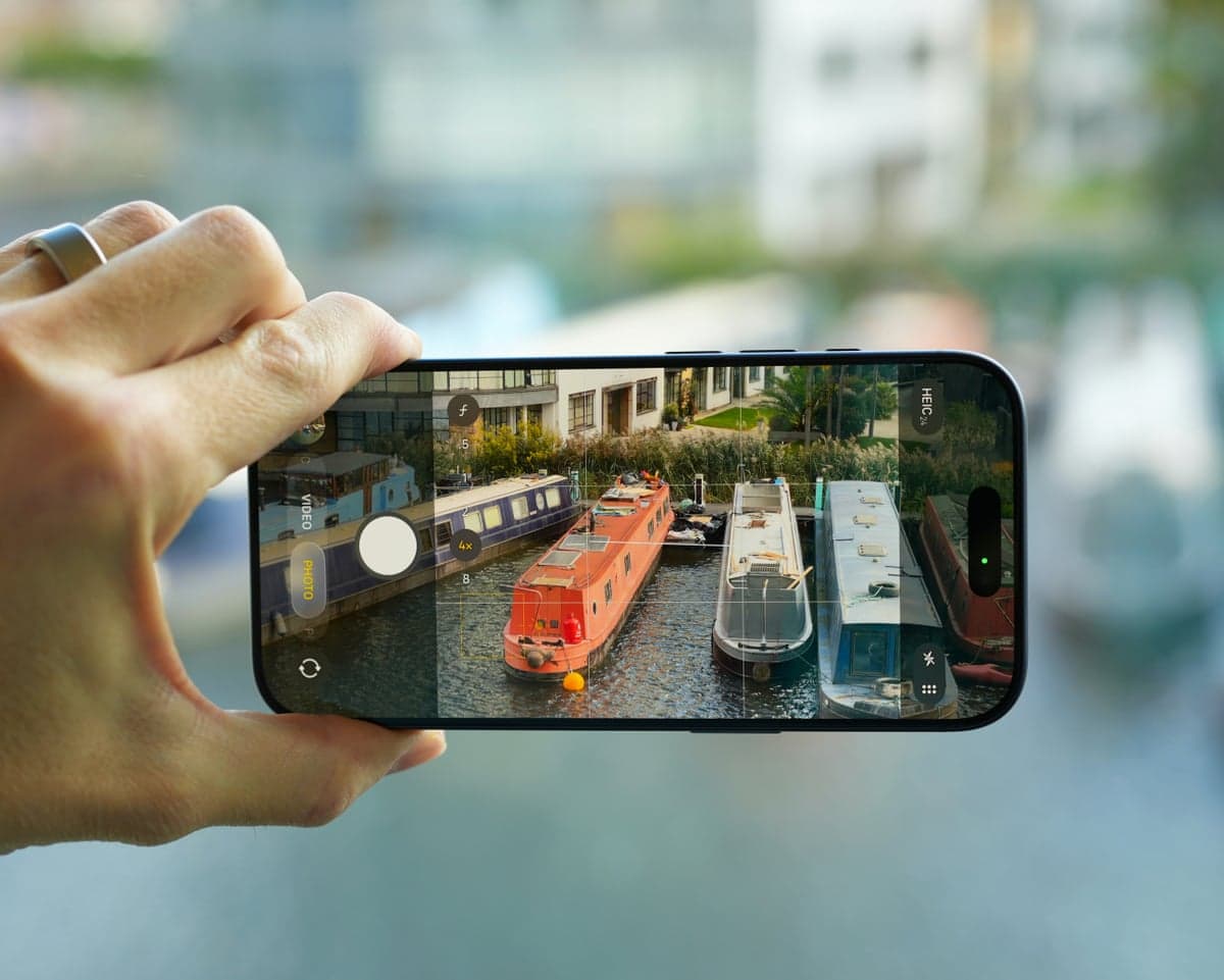 A hand holding an Apple iPhone 17 focusing on narrow boats for a picture