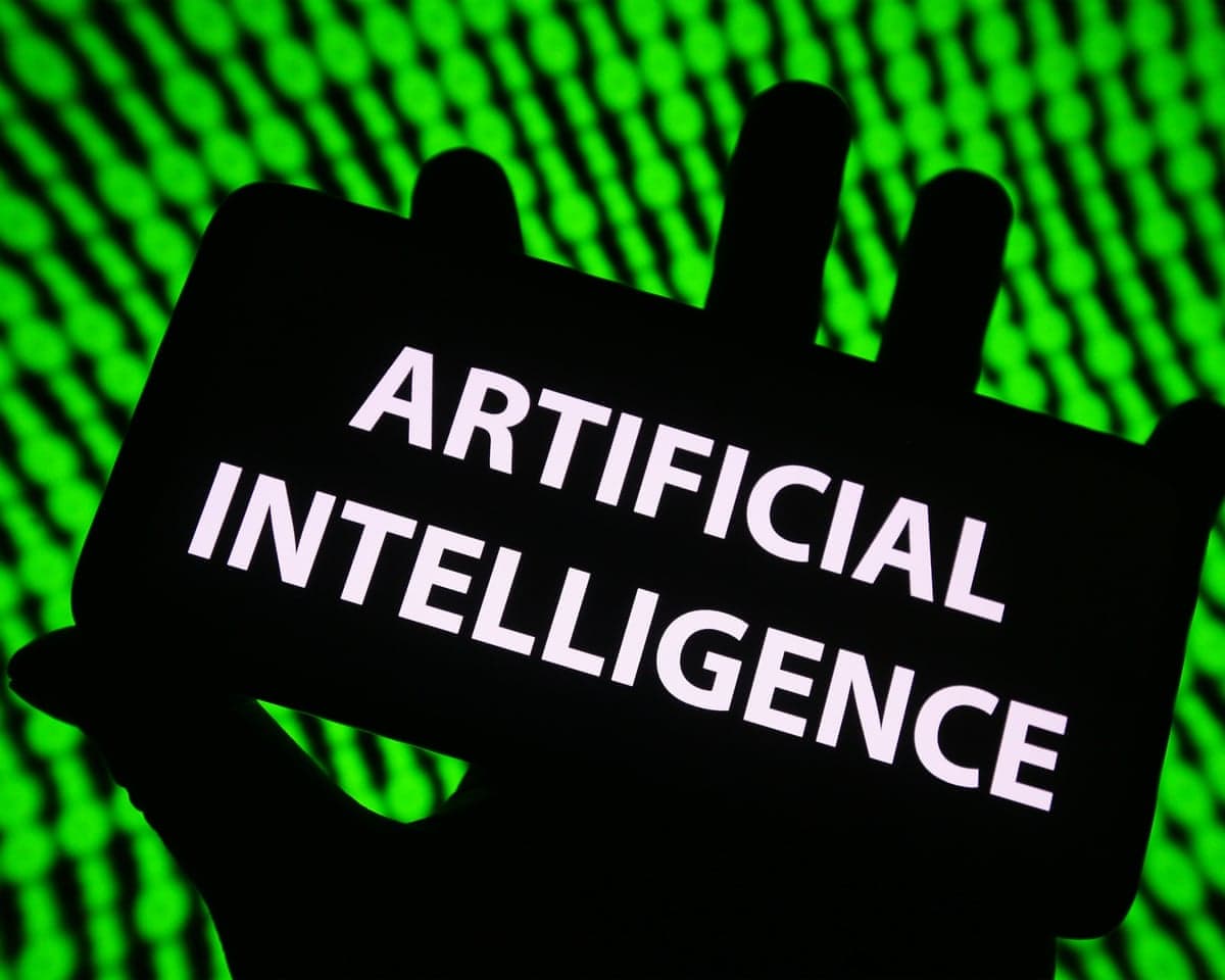 The words artificial intelligence are displayed on a smartphone being held