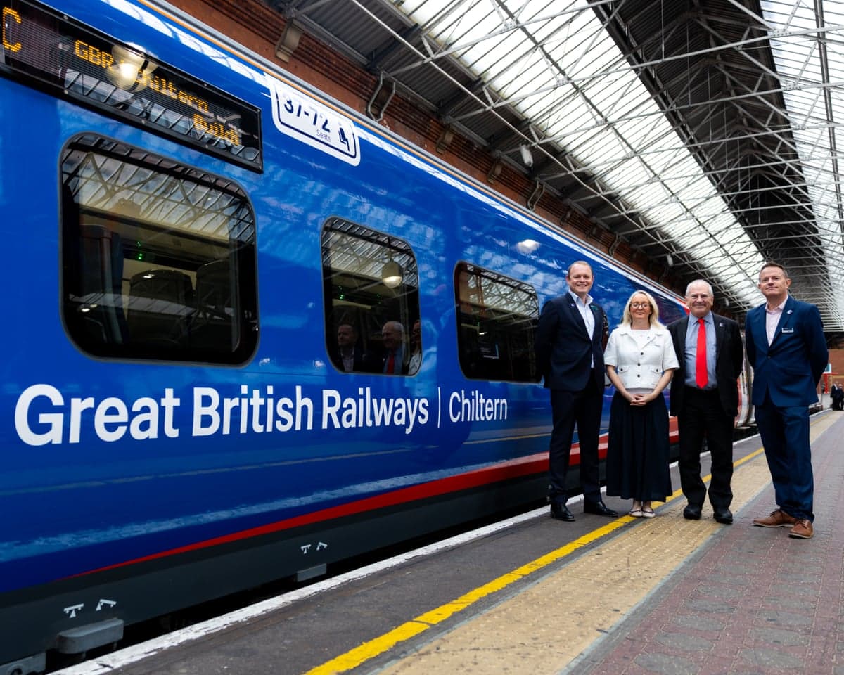 Peter Hendy and three others stand by a blue-coloured train carriage with lettering that reads: 'Great British Railways | Chiltern'