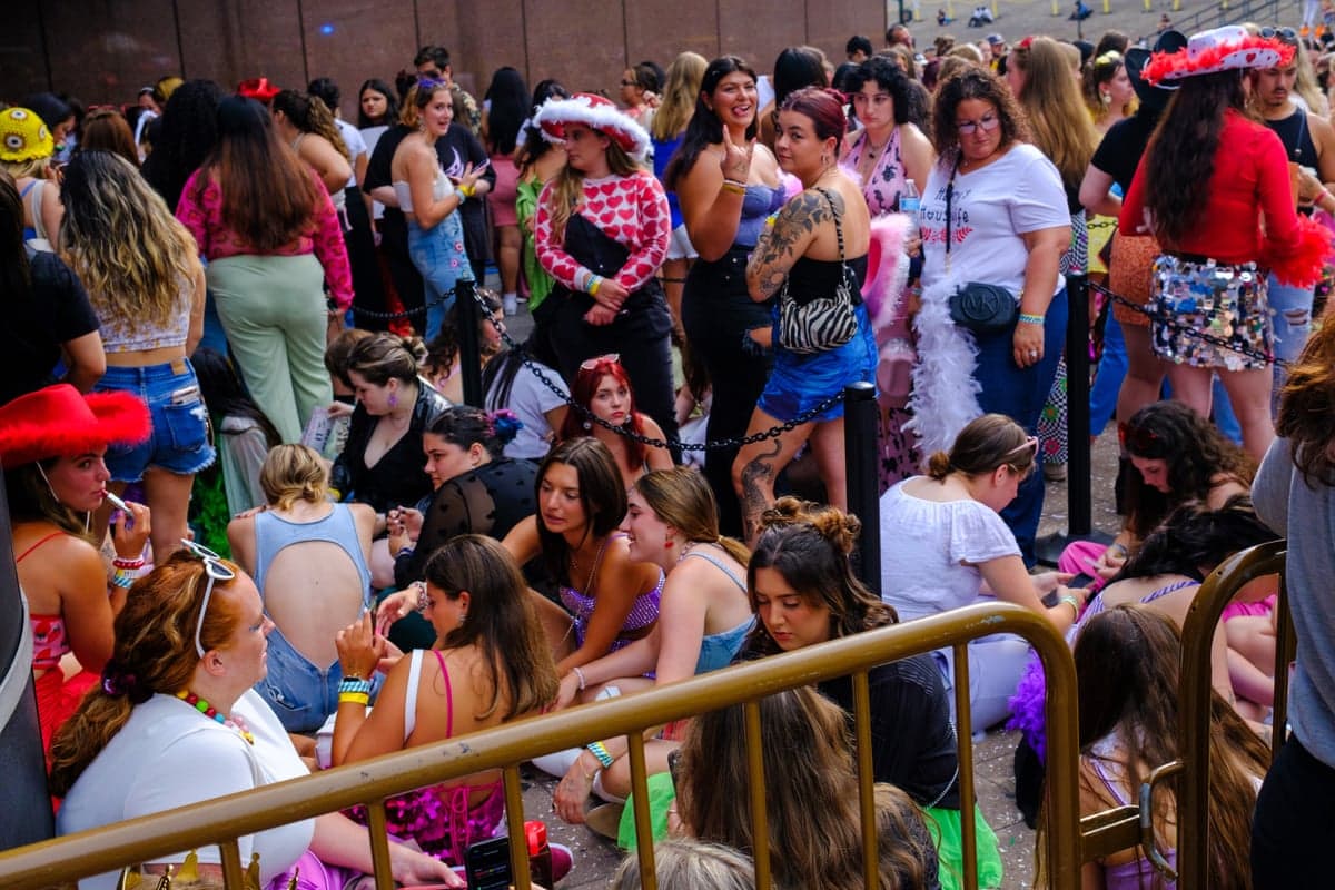fans sit and stand outside a stadium
