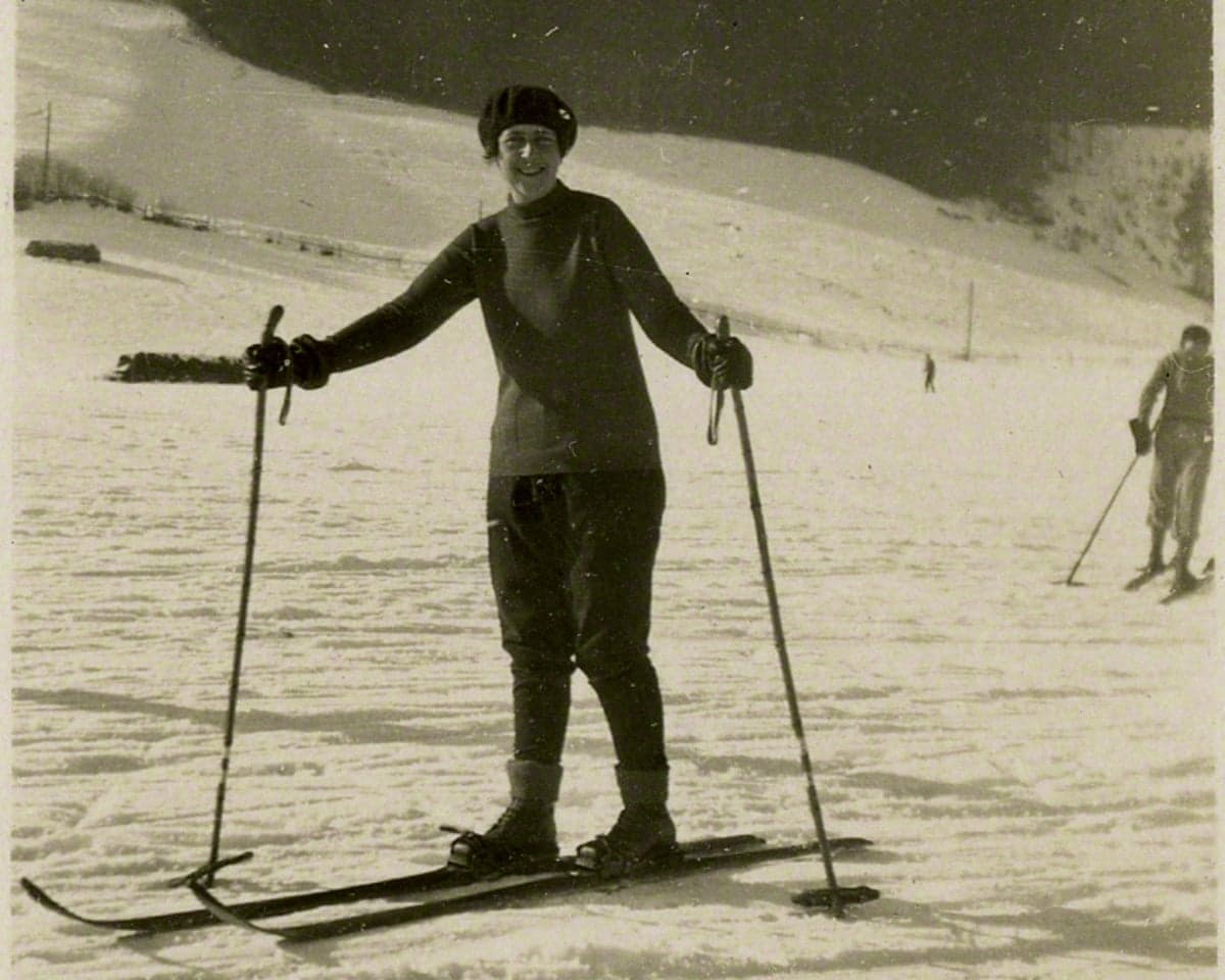 Agatha Christie stands on skis holding poles on a snowy slope