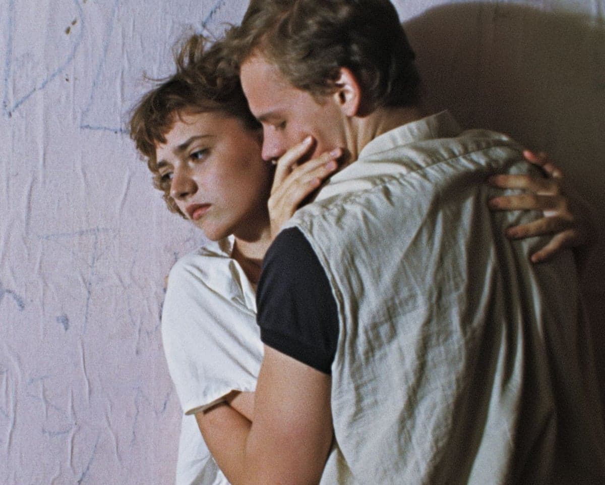 Film still from Smile at Last: a young woman rests her head on a man's shoulder as he embraces her