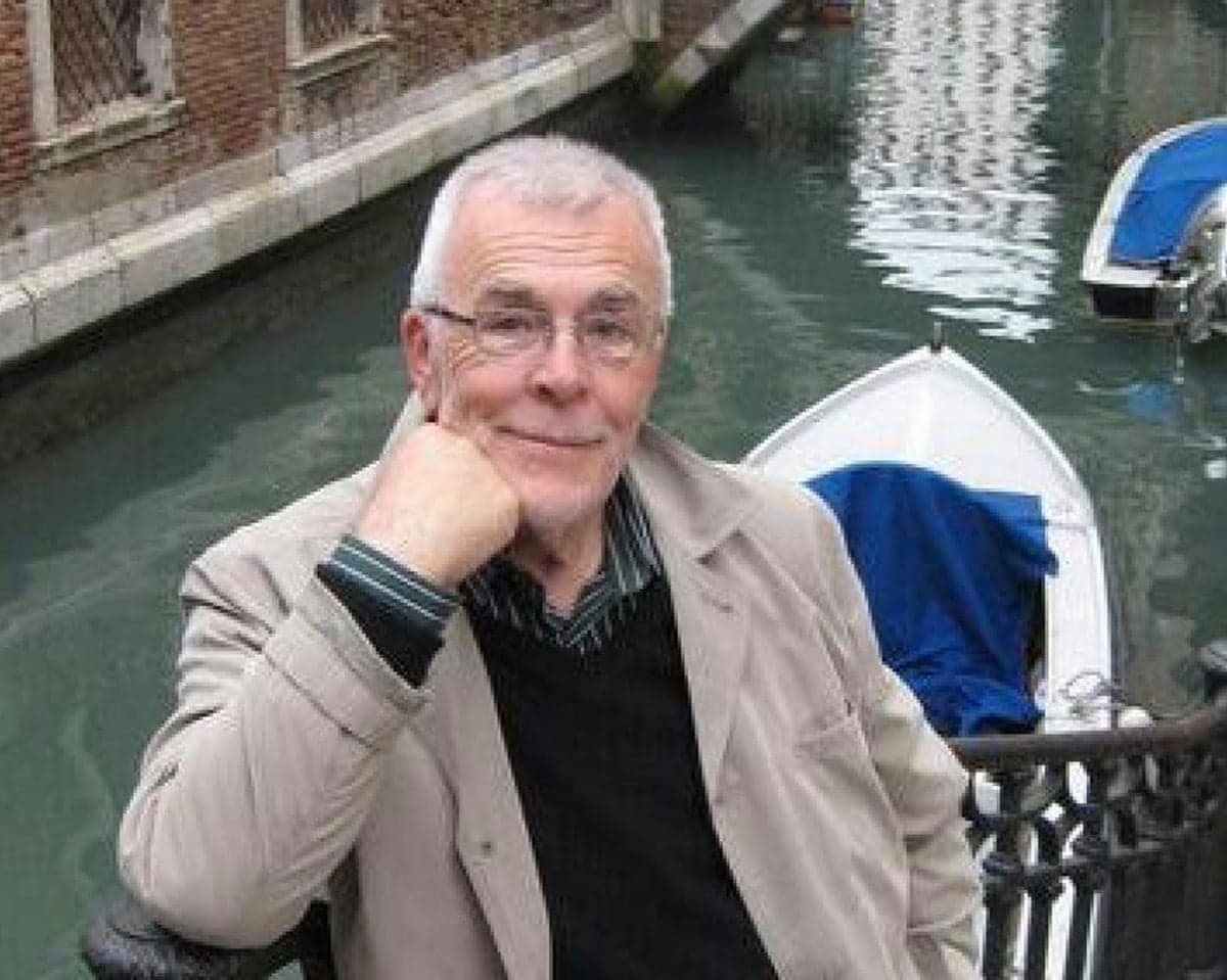 Brian Potter rests his chin on his hand while sitting by a canal with boats