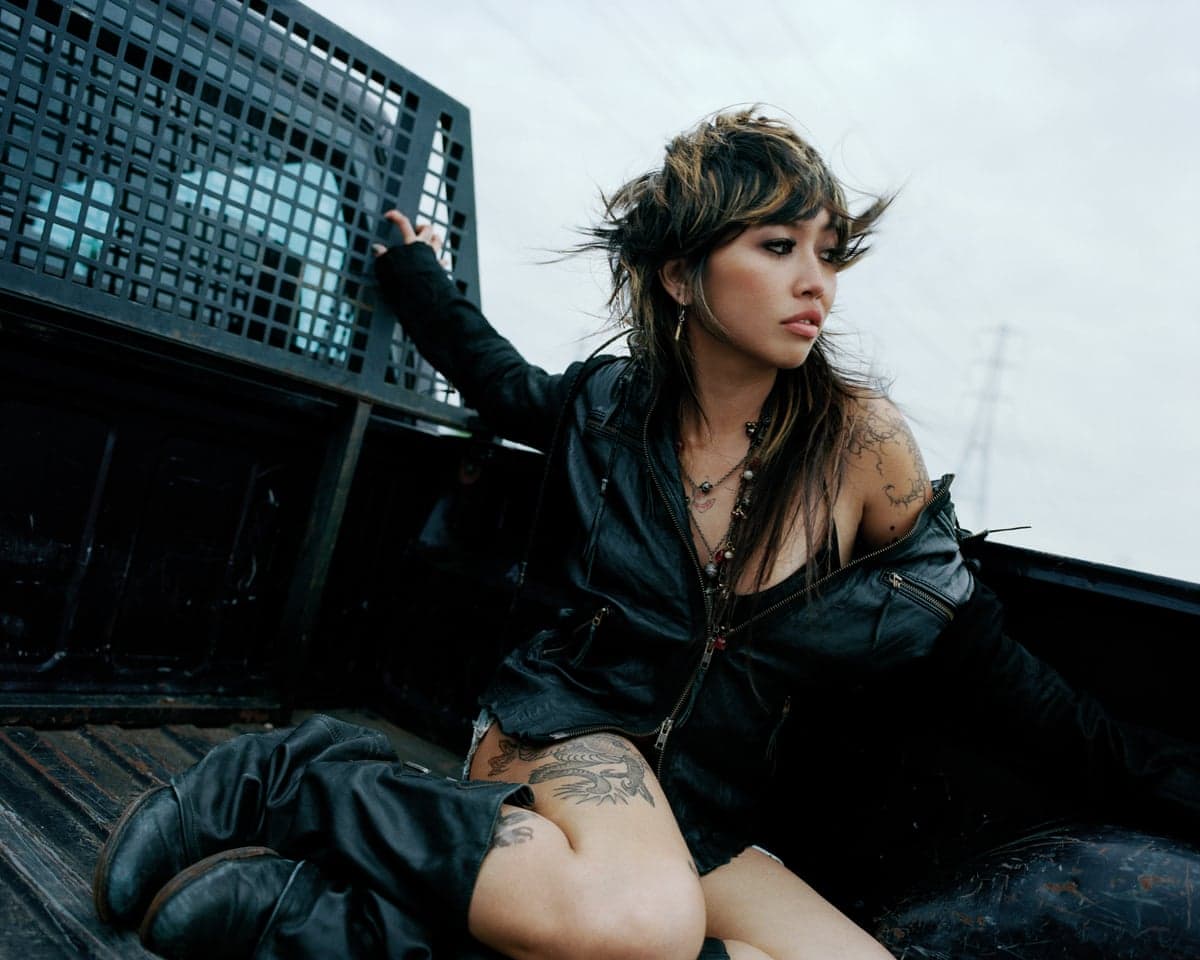The musician Beabadoobee, her hair in a streaked mullet, in the back of an open flatbed truck