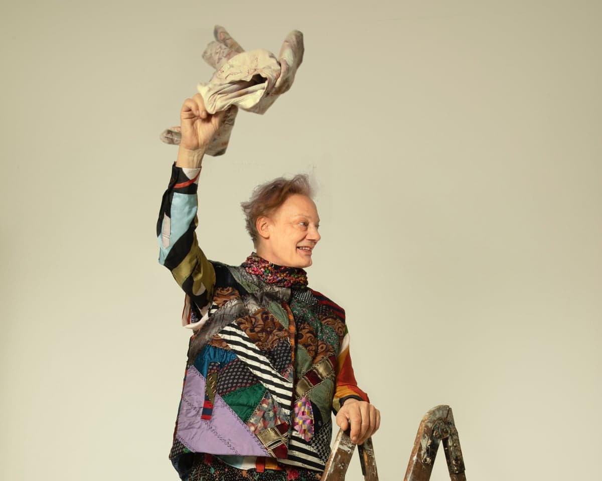 William Orbit standing on a ladder and waving an object
