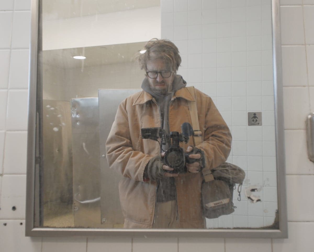 a man with a camera in a dusty mirror