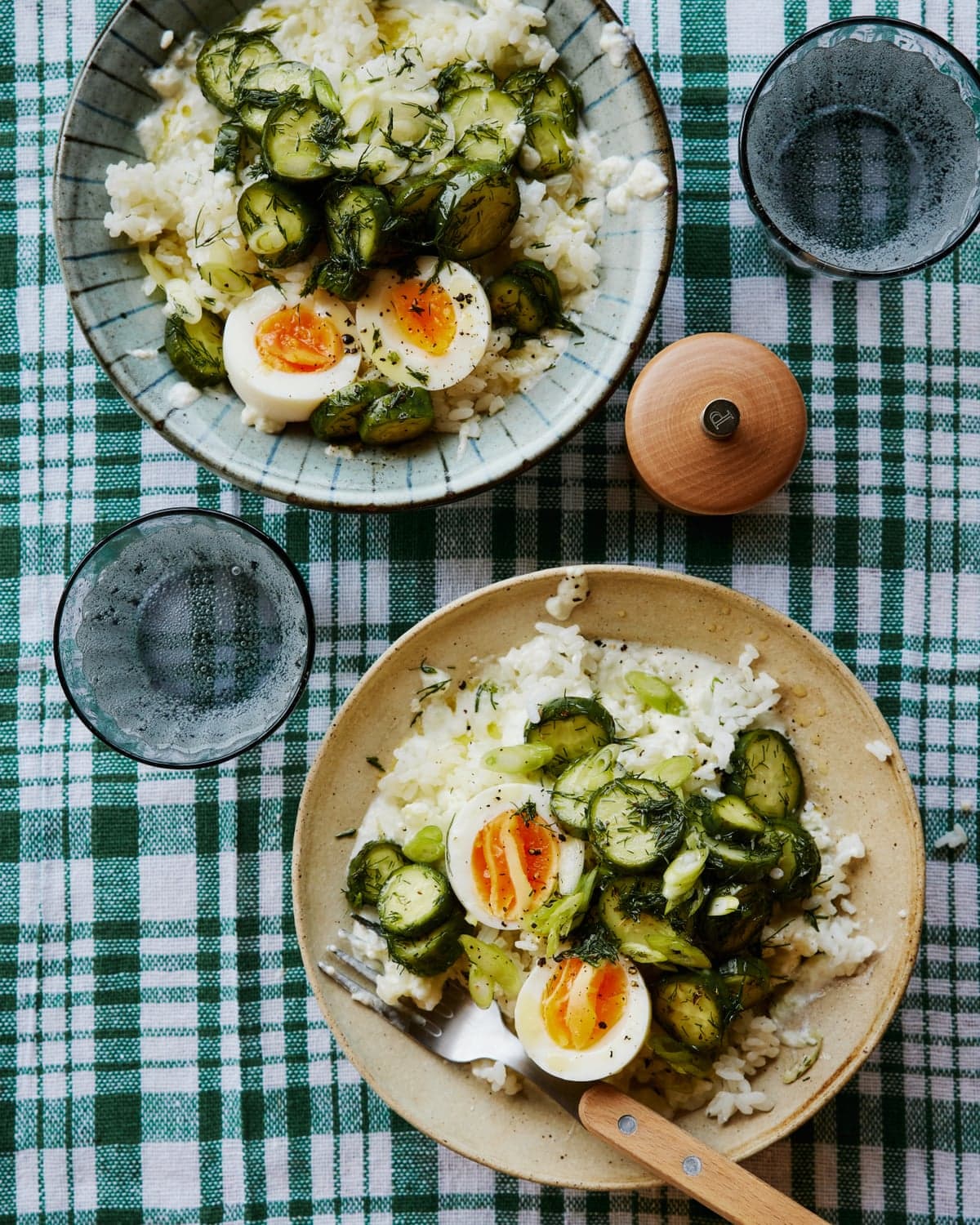 Rosie Mackean's cucumber rice dish in two bowls on a check tablecloth, with glasses and other items on the table