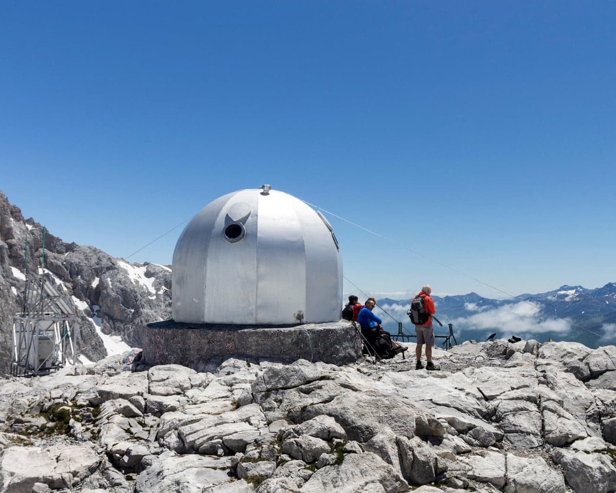 A silver dome-shaped building on a rocky mountaintop