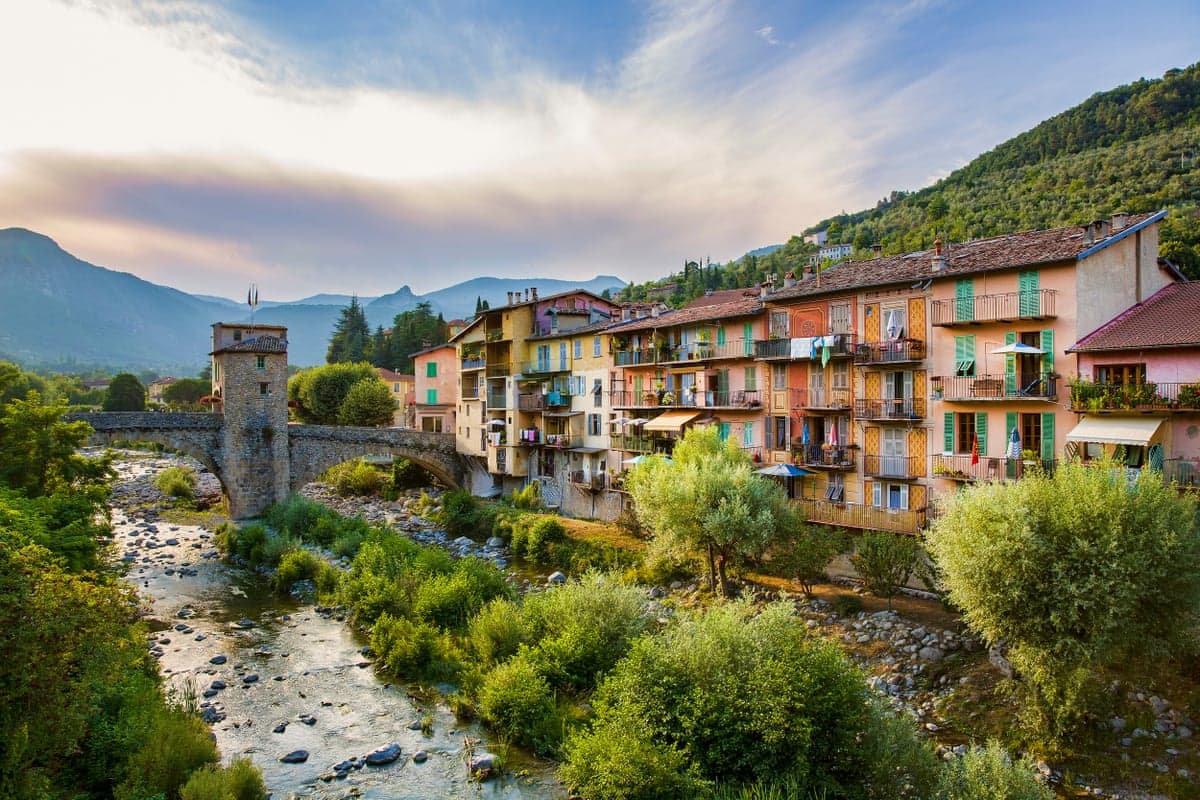 Old village in mountains at dusk with ancient bridge over a river
