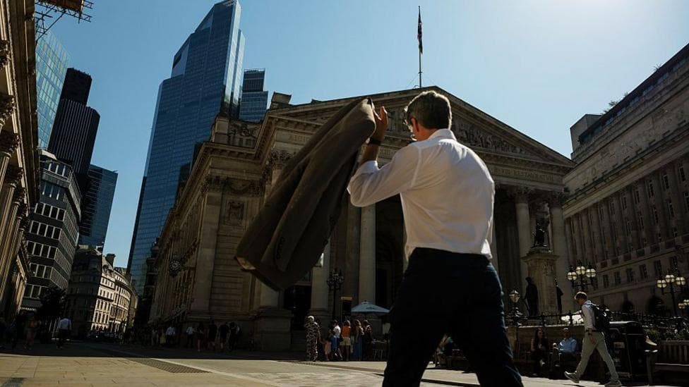 A commuter carries his jacket on a sunny day in the City of London
