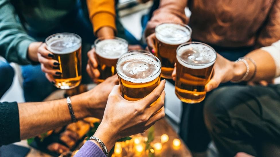 A group all holding pints of beer, with the image a close-up of their hands.