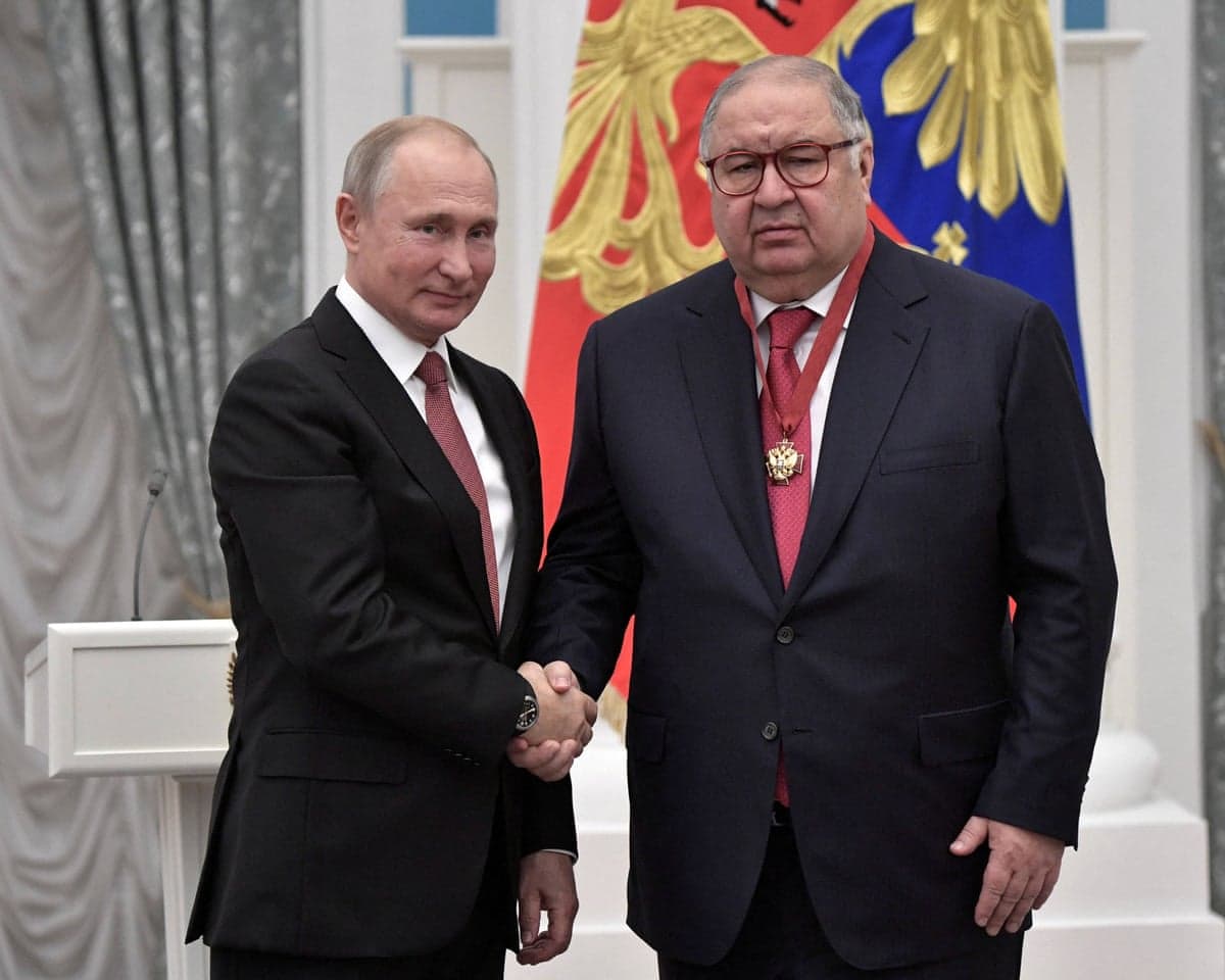 Putin shakes hands with Alisher Usmanov, who wears a medal on a red ribbon