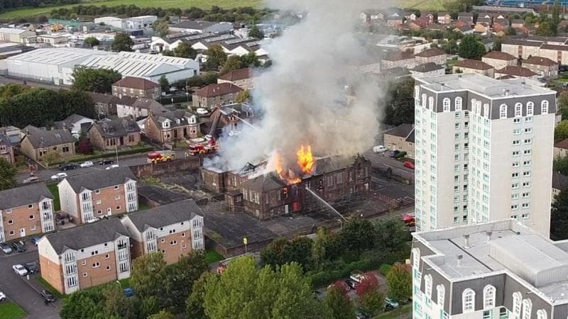 Flames rising from the roof of a burning building, shot from a drone