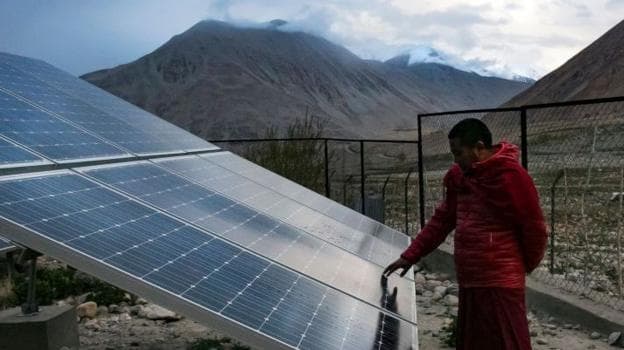A monk touches solar panels at the Shachukul Monastery in the Ladakh region