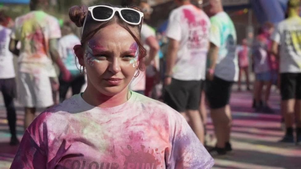 A female university student covered in pain. She is participating in a fun run event.