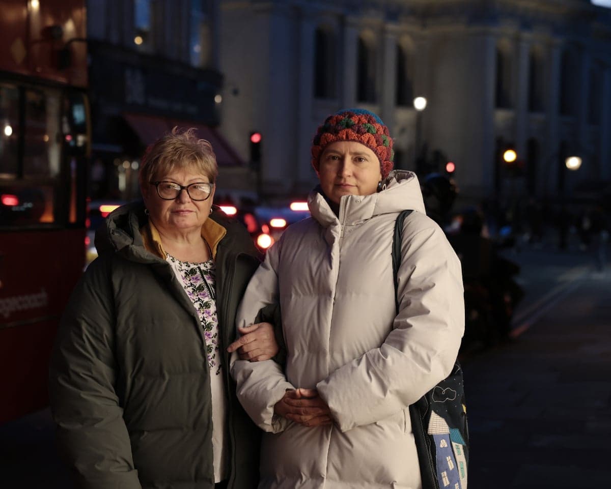 Nataliya Rumyantseva and her mother, Valentyna Klymova, stand on a dark street in winter coats with their arms linked.