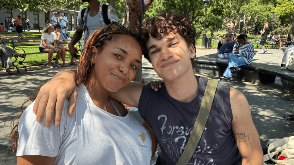 A woman and a man sit on a bench in a park