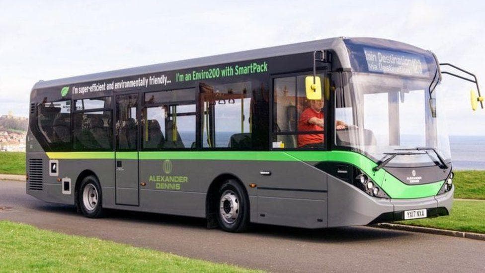 a grey electric bus with a green line and writing across it. It has an Alexander Dennis logo on the side.